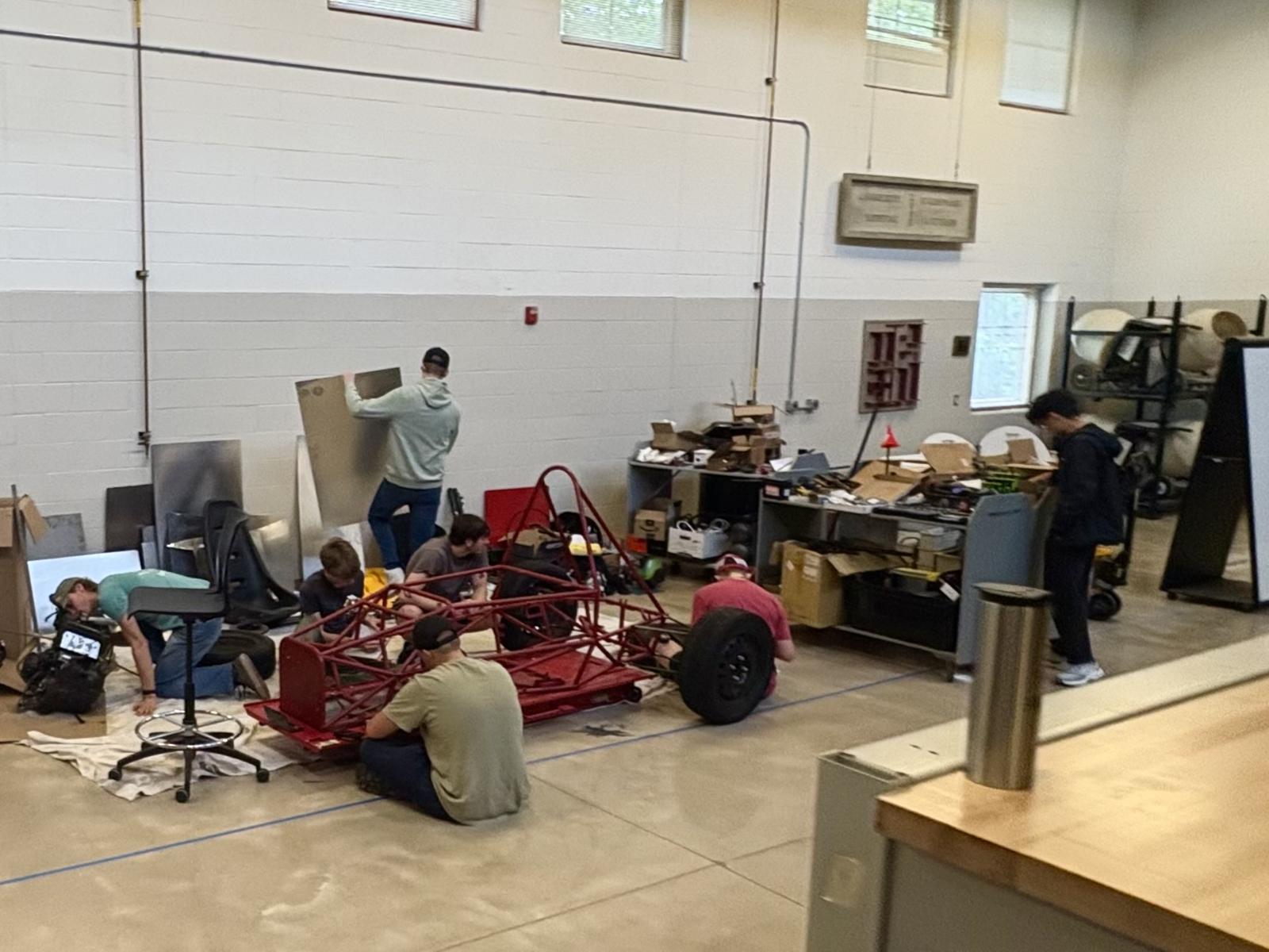Chassis and Suspension members working on the red frame on the shop floor