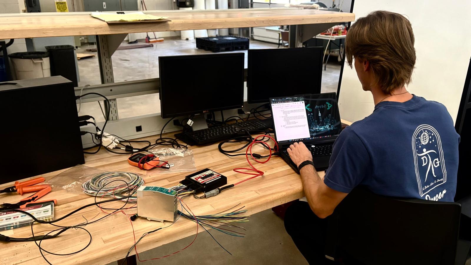 Electrical lead at a bench with the ECU, a power supply, and wiring