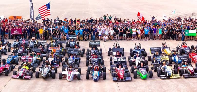 Dozens of Formula SAE cars lined up in front of hundreds of student team members at a competition