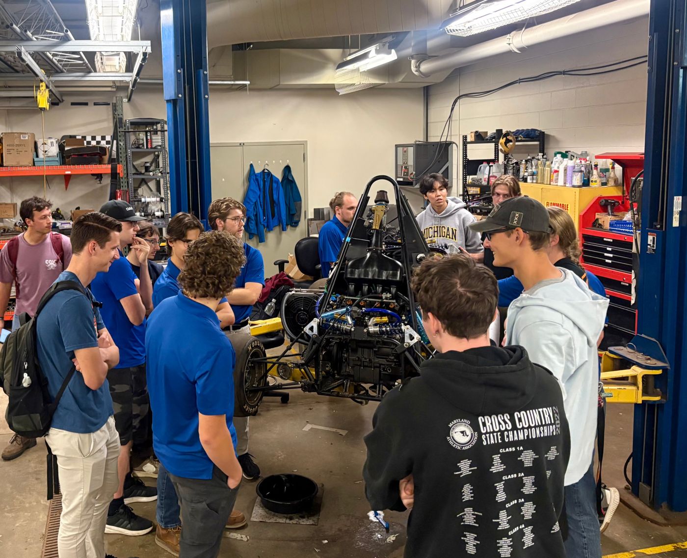 Calvin members gathered around Laker Racing's car in Grand Valley's shop