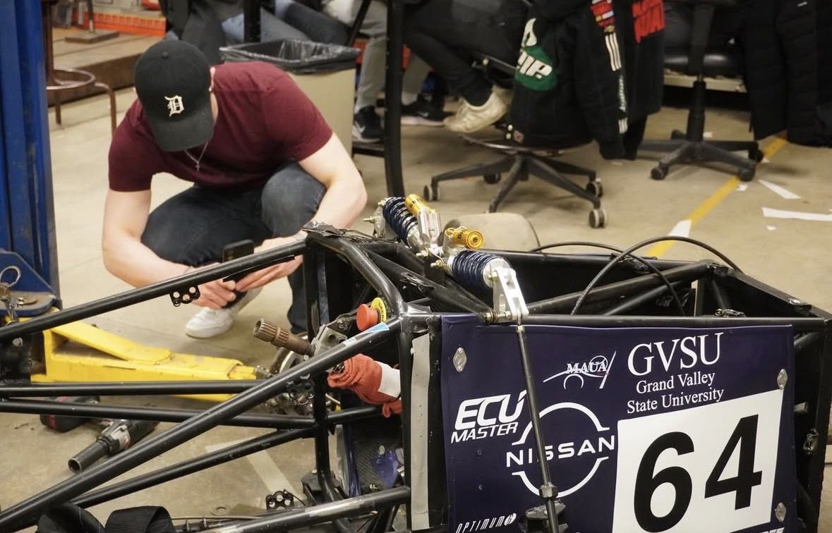A Calvin member inspecting the wiring on Laker Racing's car number 64