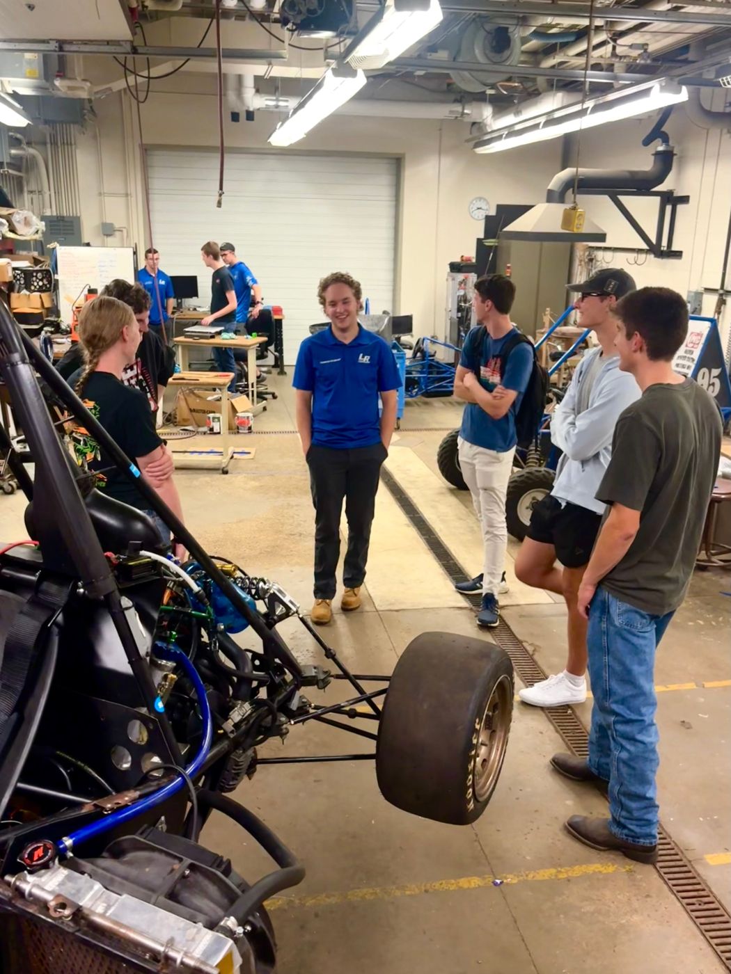 A Laker Racing member talking with Calvin students beside their car
