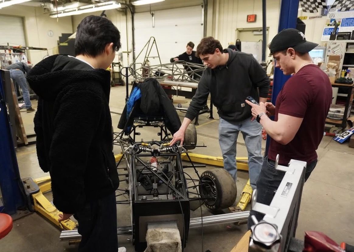 Calvin members looking over a chassis in Grand Valley's shop