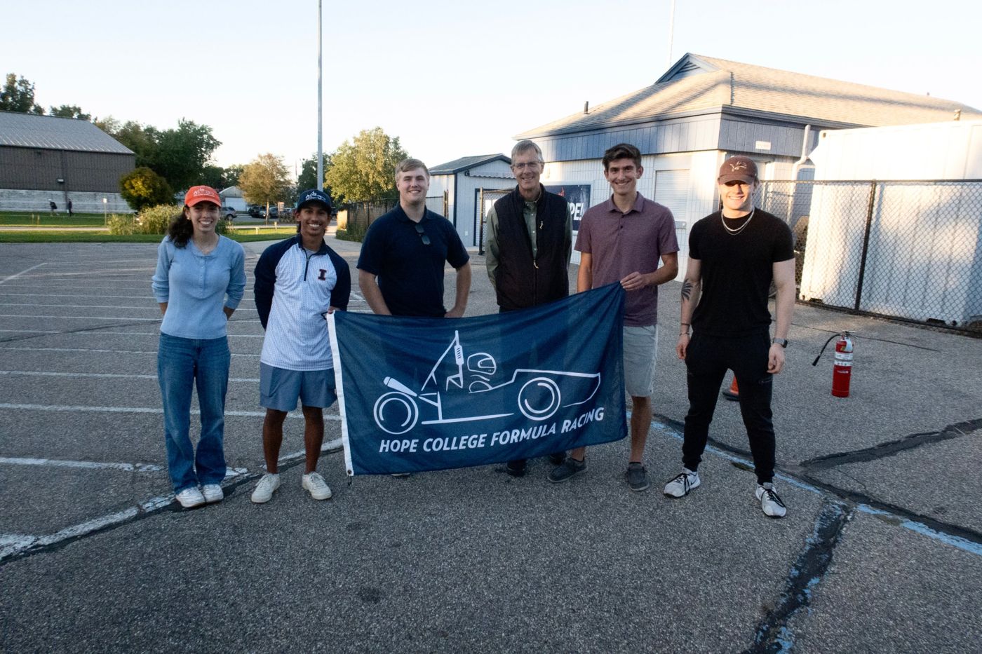 Calvin and Hope members holding the Hope College Formula Racing flag