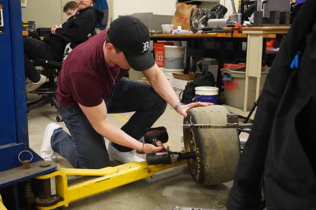A member using an impact wrench on a racing wheel